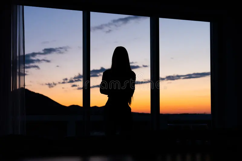 silhueta de uma mulher parada em frente janela com o por do sol ao fundo jovem pe na no 191064812
